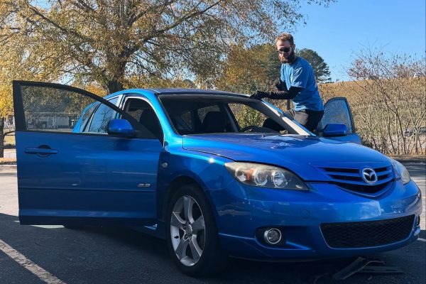 A Person In A Blue Car Parked In A Parking Lot